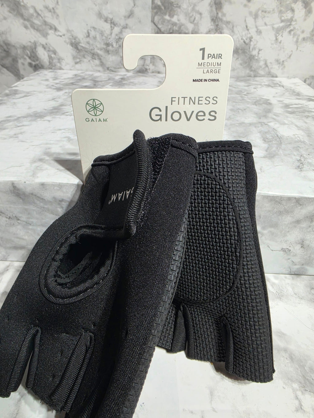 Black fitness gloves with a brand label on a marble surface