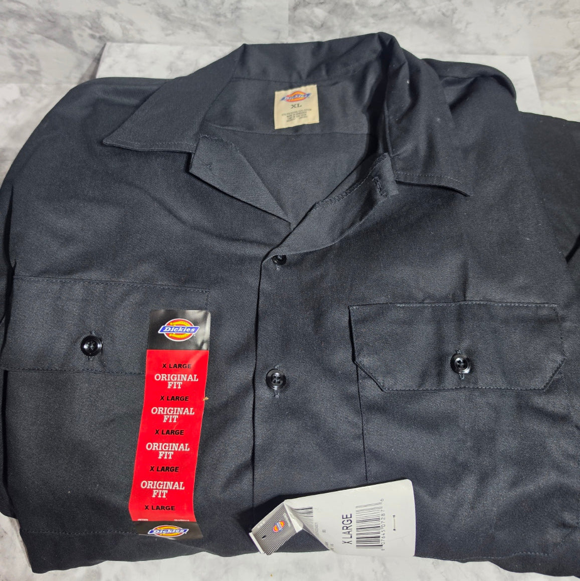 Dark gray work shirt with Dickies branding on a textured surface