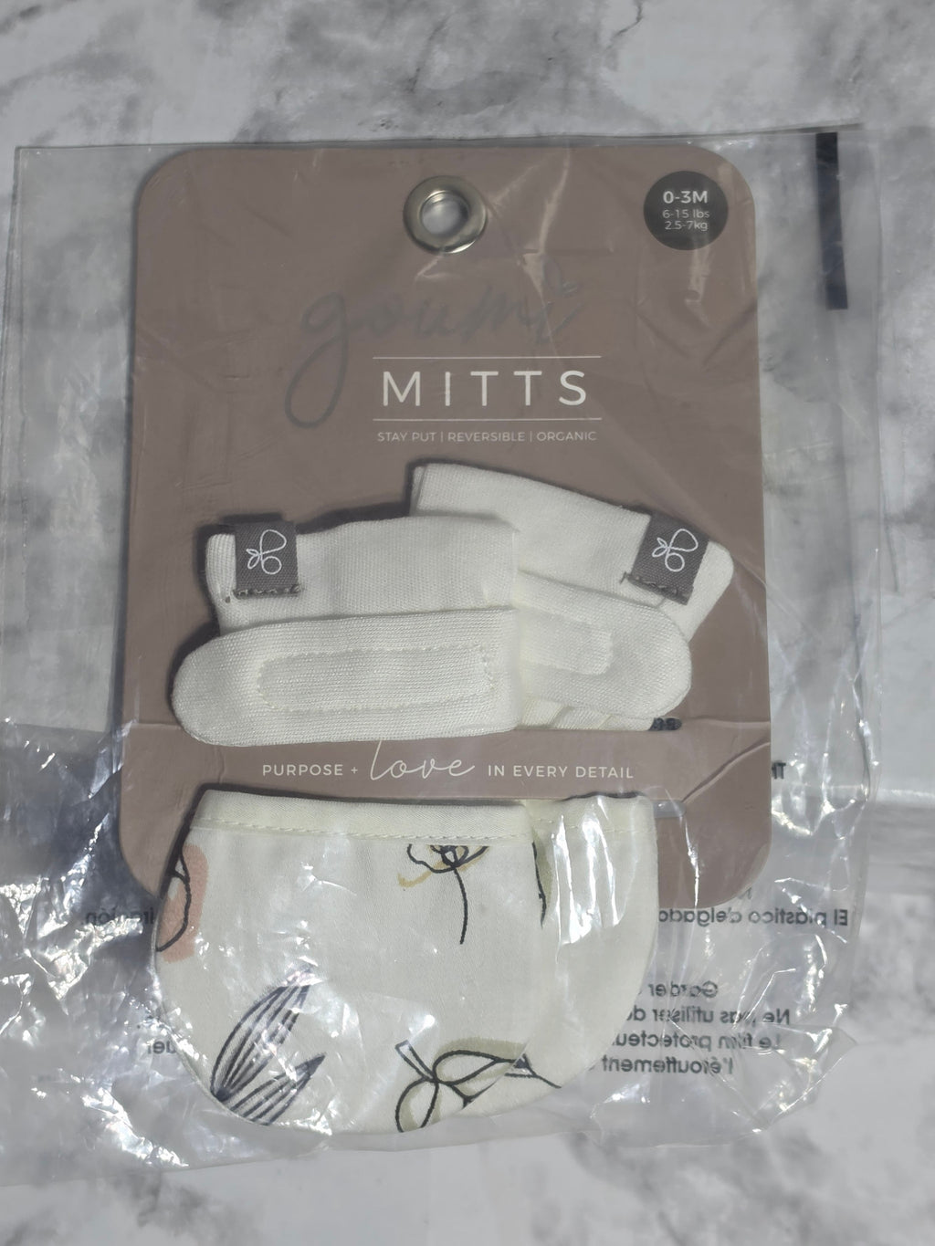 Pair of white gloves in packaging on a marble surface