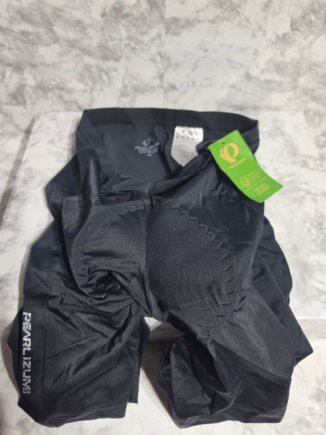Black cycling shorts with a green tag on a gray surface