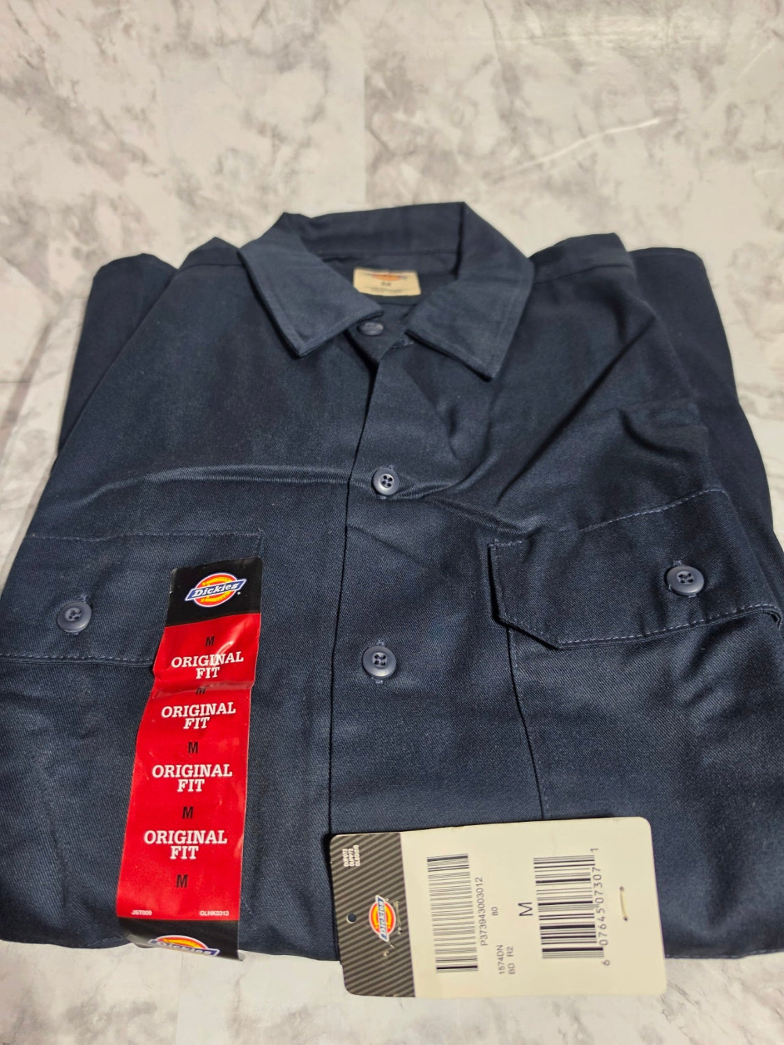 Folded navy blue shirt with Dickies branding on a textured surface