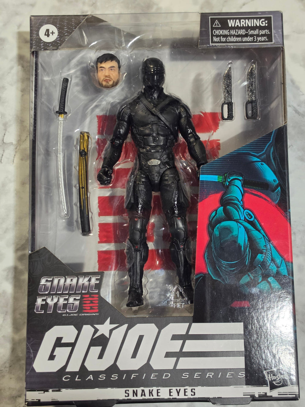 G.I. Joe action figure in packaging with 'Snake Eyes' branding.