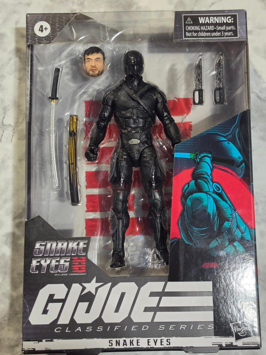 G.I. Joe action figure in packaging with 'Snake Eyes' branding.