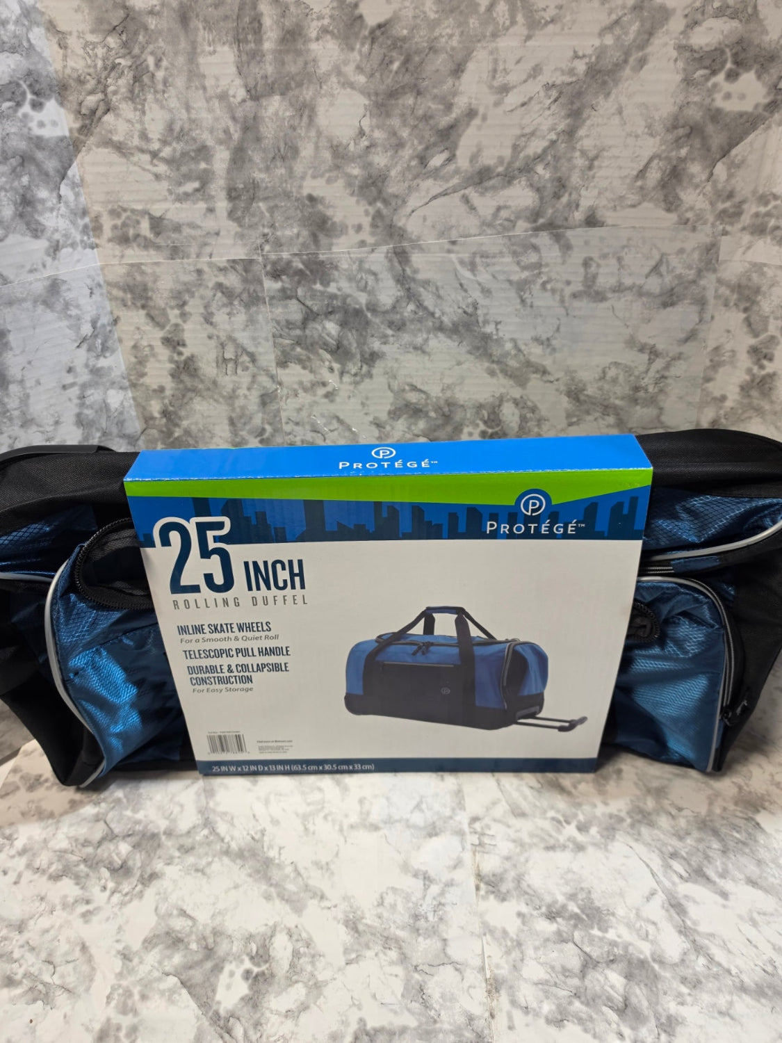 Blue duffel bag with packaging labeled '25 Inch' on a marble surface