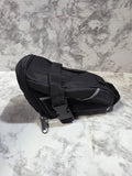 Actual black Schwinn bicycle seat pack with zippered compartment, buckle straps and reflective piping on gray marble
