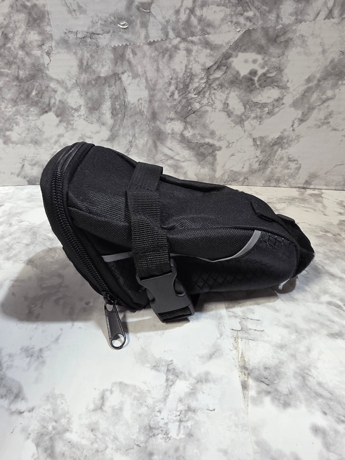Black sandal with a strap on a textured gray surface