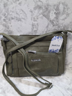 Green crossbody bag with a visible brand tag on a marble surface