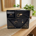 AI-staged scene: Collection XIIX black three-piece boxed gift set on an entryway console; props not included.