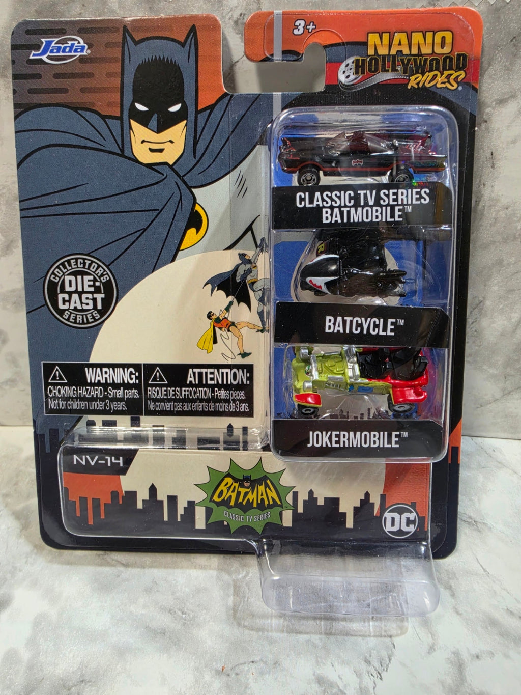 Toy vehicle set in packaging with Batman branding on a marble surface