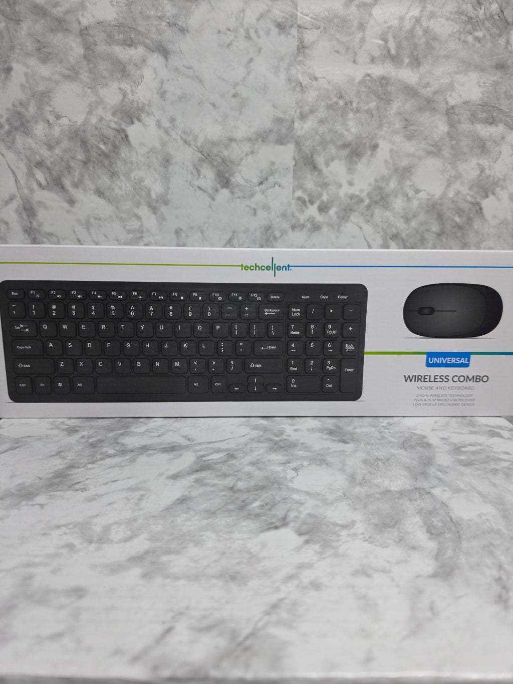 Keyboard and mouse set on a marble surface with packaging in the background
