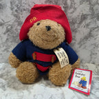 Teddy bear wearing a red and blue outfit with a tag on a marble surface