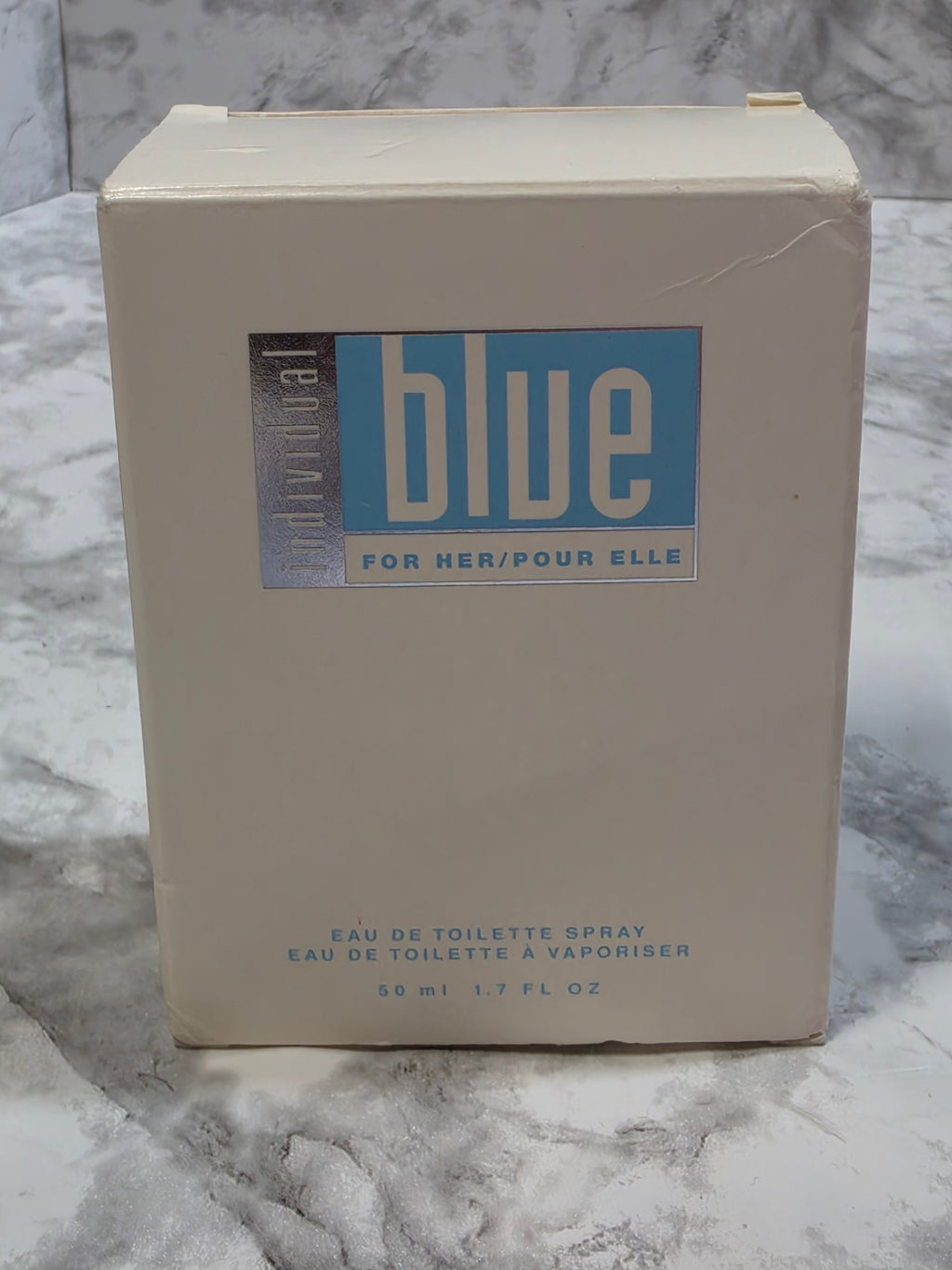 Je Ne Laisse Blue perfume box on a marble surface