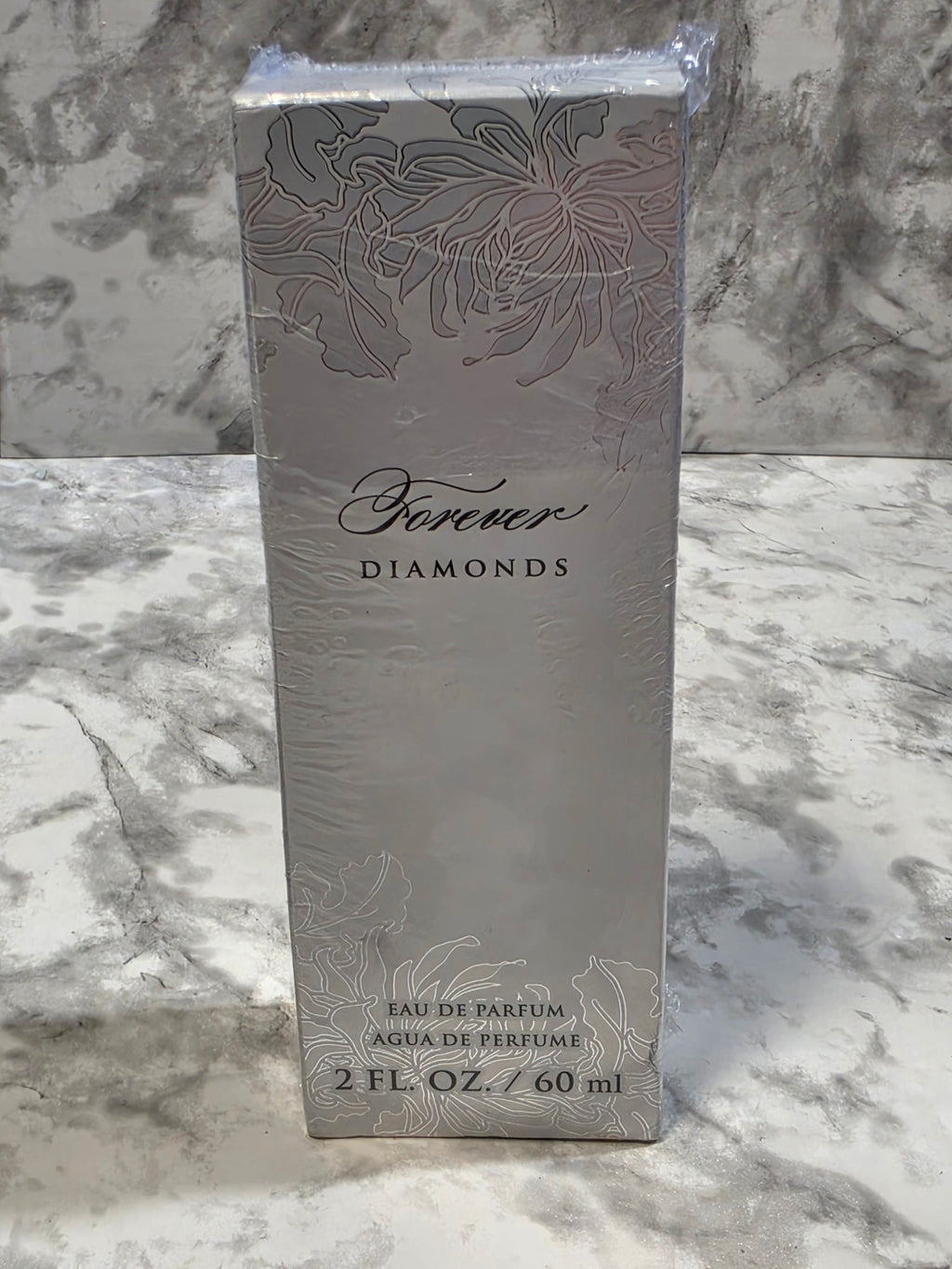 Perfume bottle packaging with floral design and brand name on a marble background