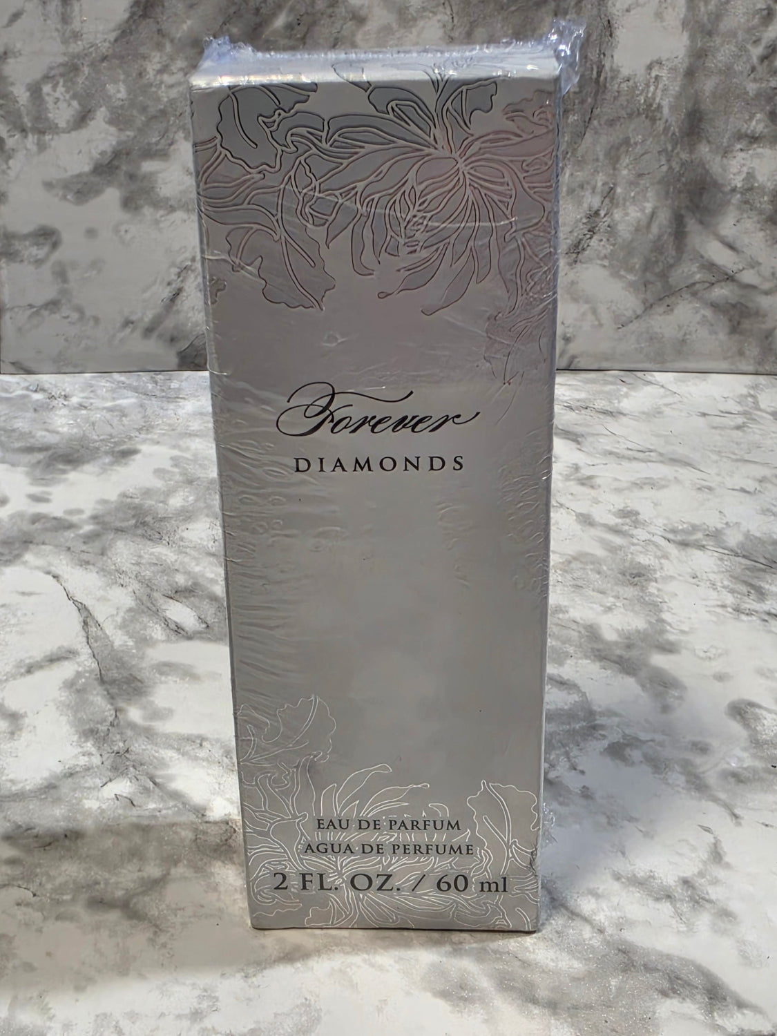 Perfume bottle packaging with floral design and brand name on a marble background