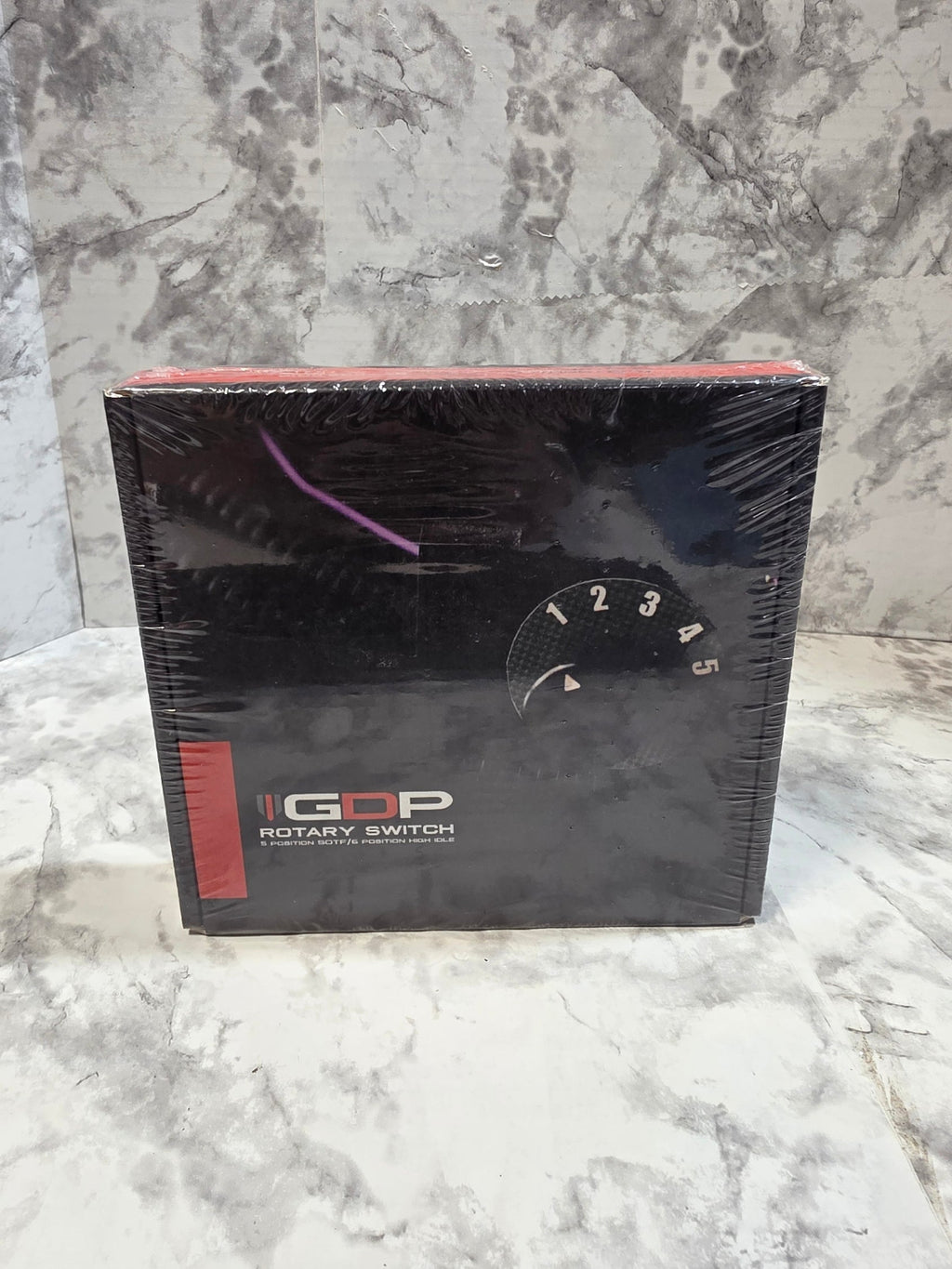Black box with a rotary watch design on a marble surface