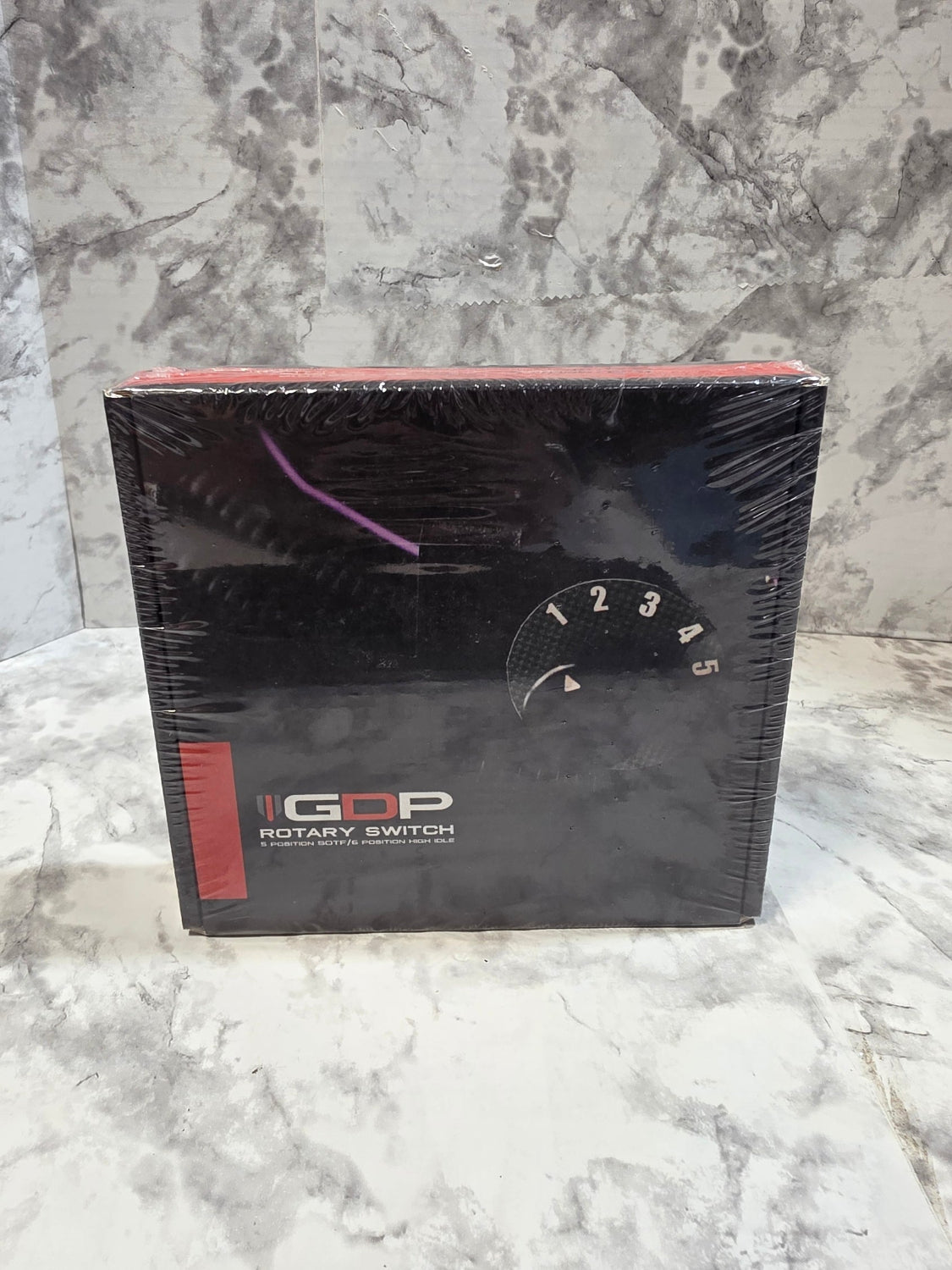 Black box with a rotary watch design on a marble surface