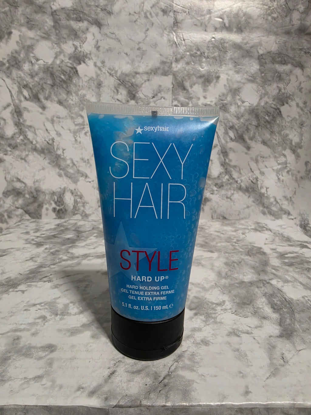 Blue hair product tube labeled 'SEXY HAIR STYLE' on a marble surface