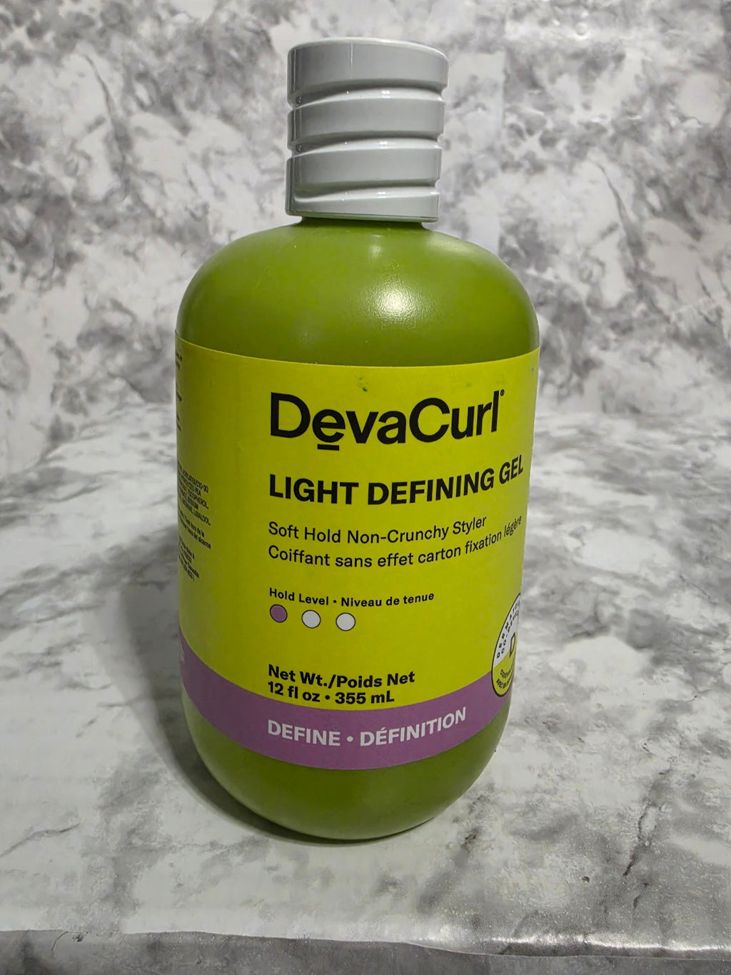 Devacurl Light Defining Gel bottle on a marble surface