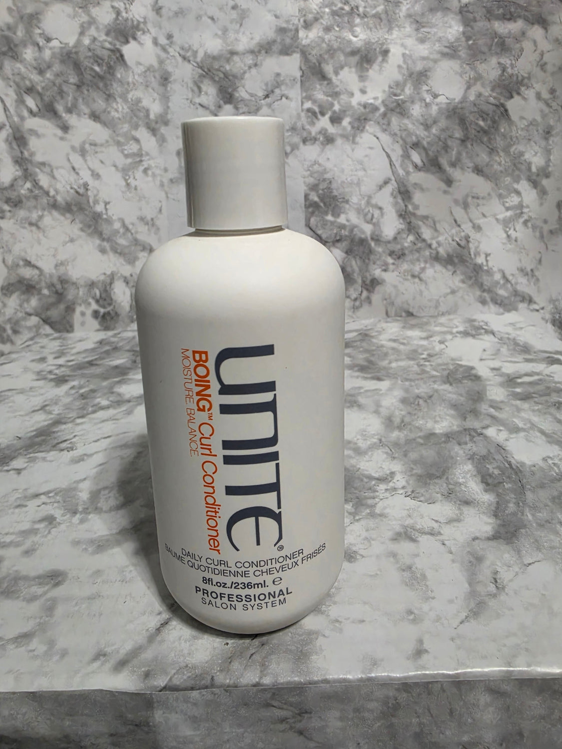 Unite Boing Curl Conditioner bottle on a marble surface