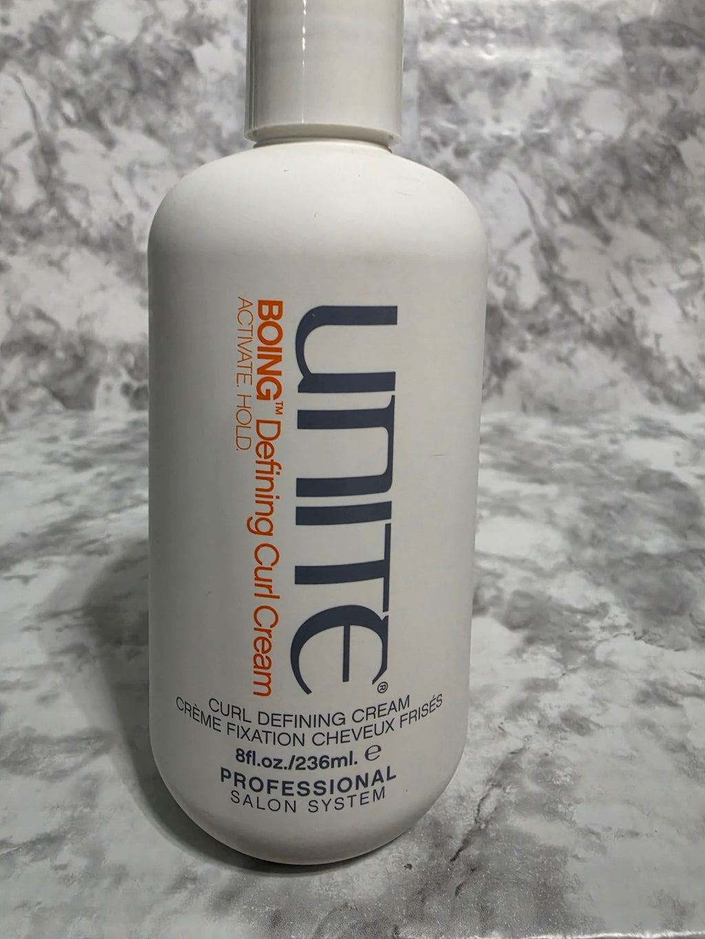 Unite Boing Defining Curl Cream bottle on a marble surface