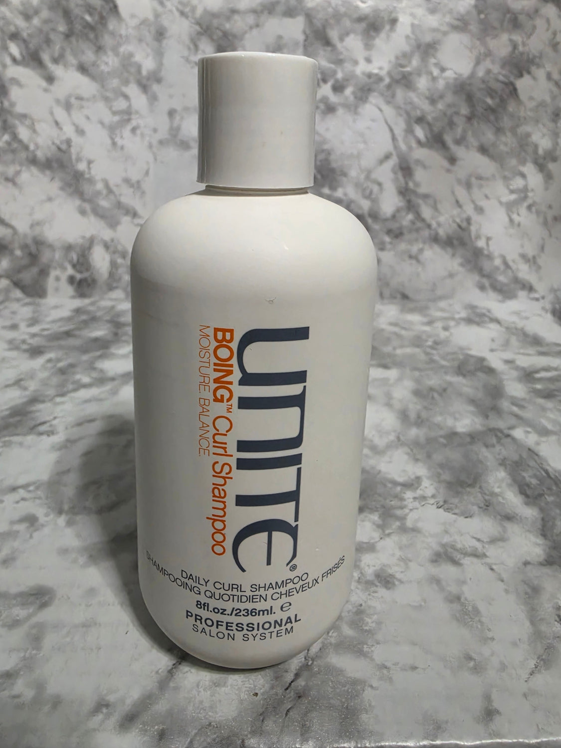 Unite Boing Curl Shampoo bottle on a marble surface