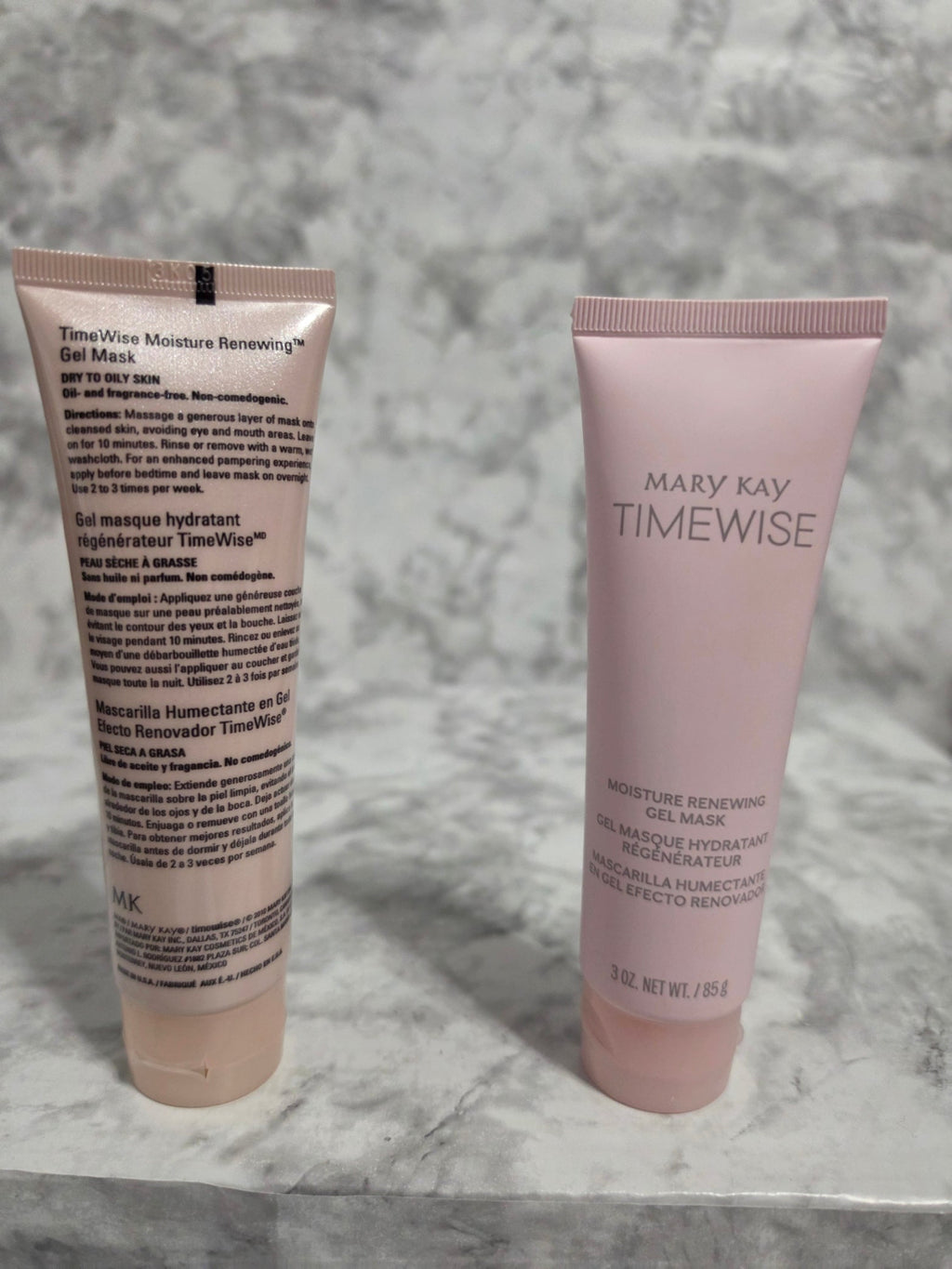 Two skincare tubes from Mary Kay on a marble surface