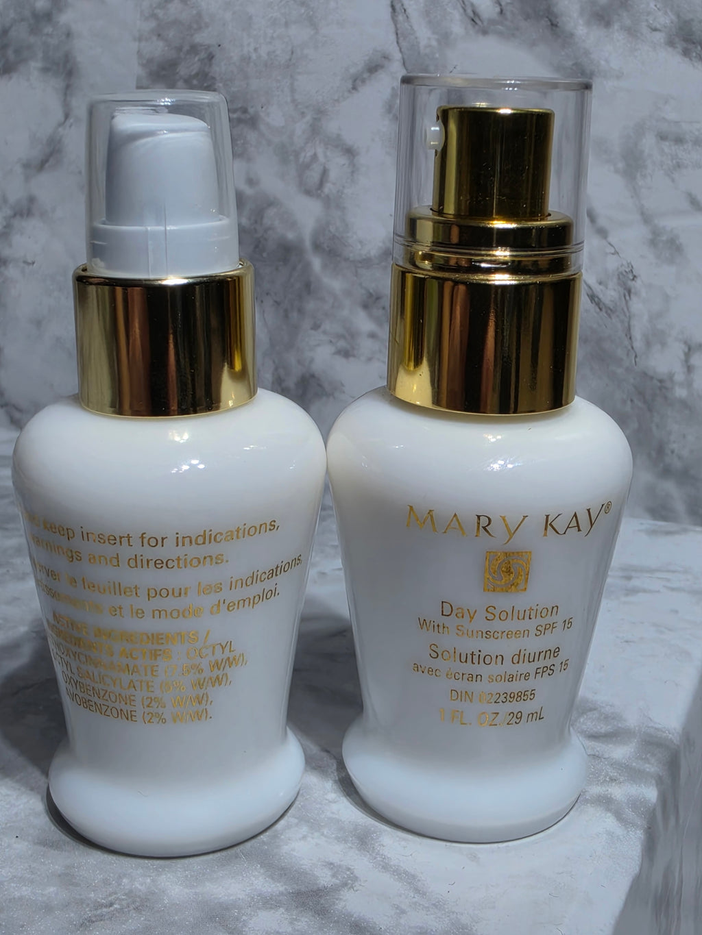 Two skincare bottles with gold caps on a marble surface