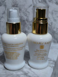 Two skincare bottles with gold caps on a marble surface