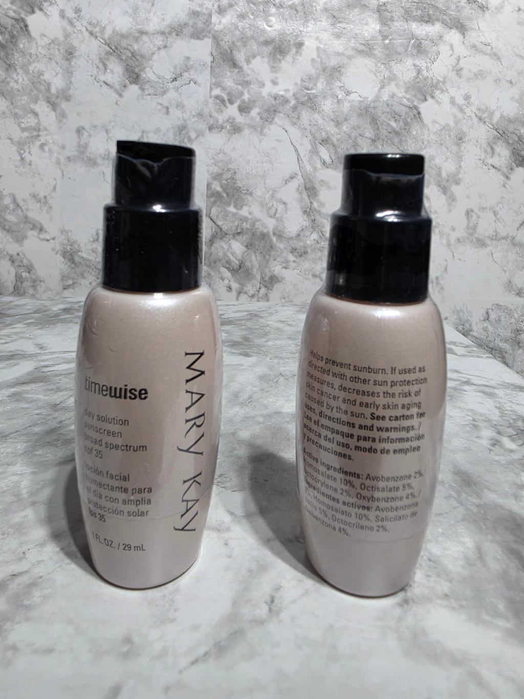 Two skincare bottles labeled 'Mary Kay' on a marble surface
