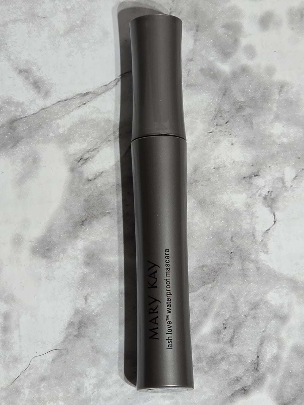 Black handheld device with 'MARY KAY' branding on a marble surface