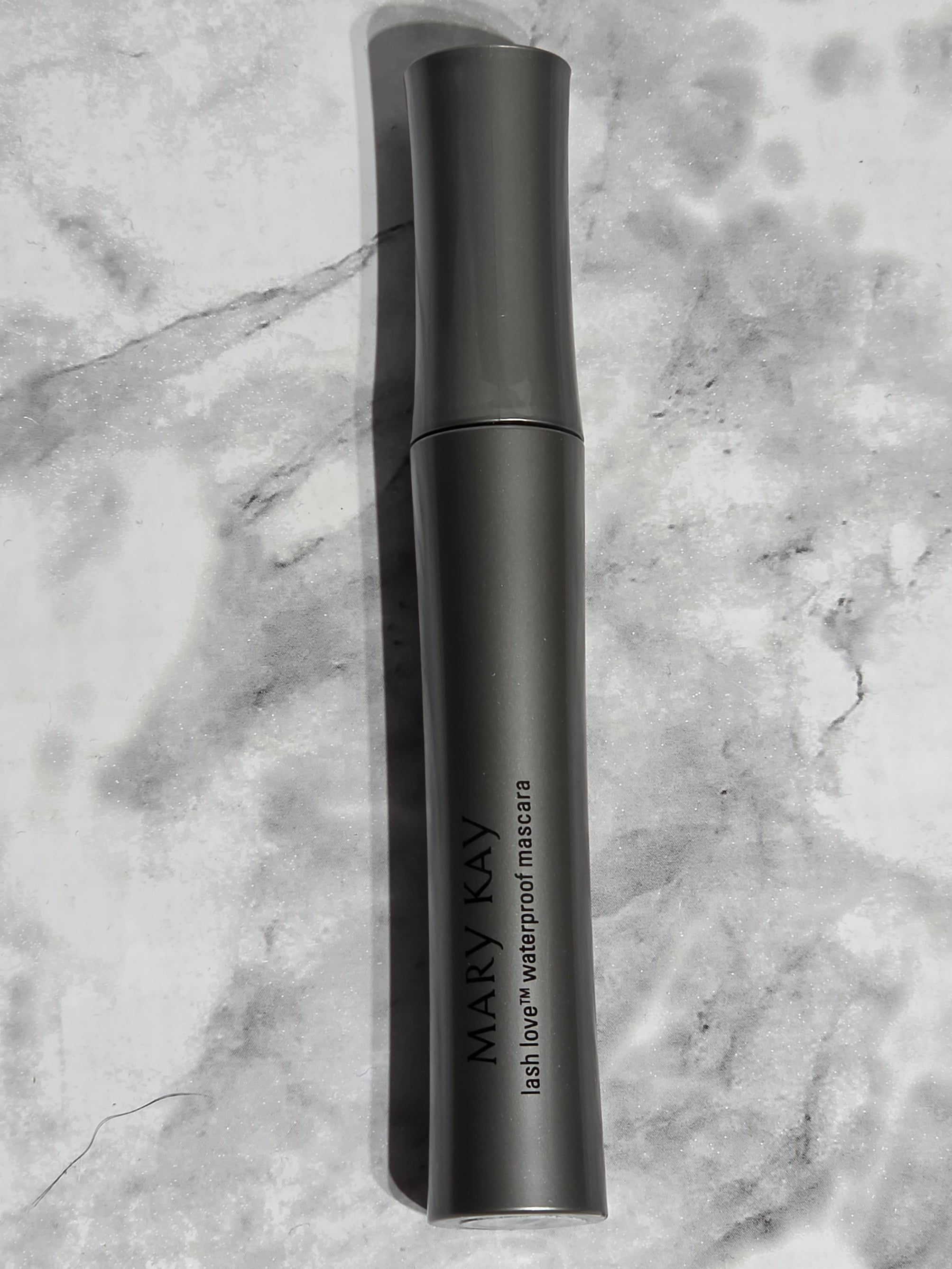 Black handheld device with 'MARY KAY' branding on a marble surface