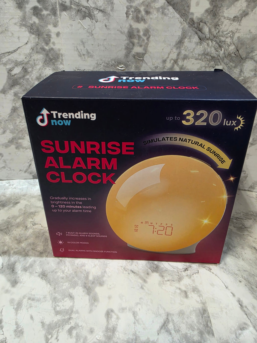 Box of a sunrise alarm clock with digital display on a marble surface