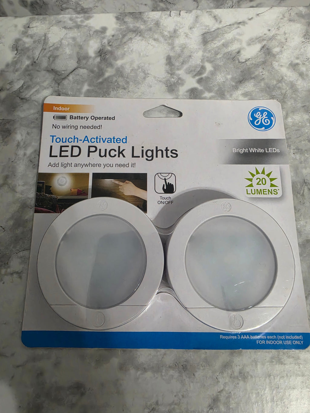 GE LED puck lights packaging on a marble surface