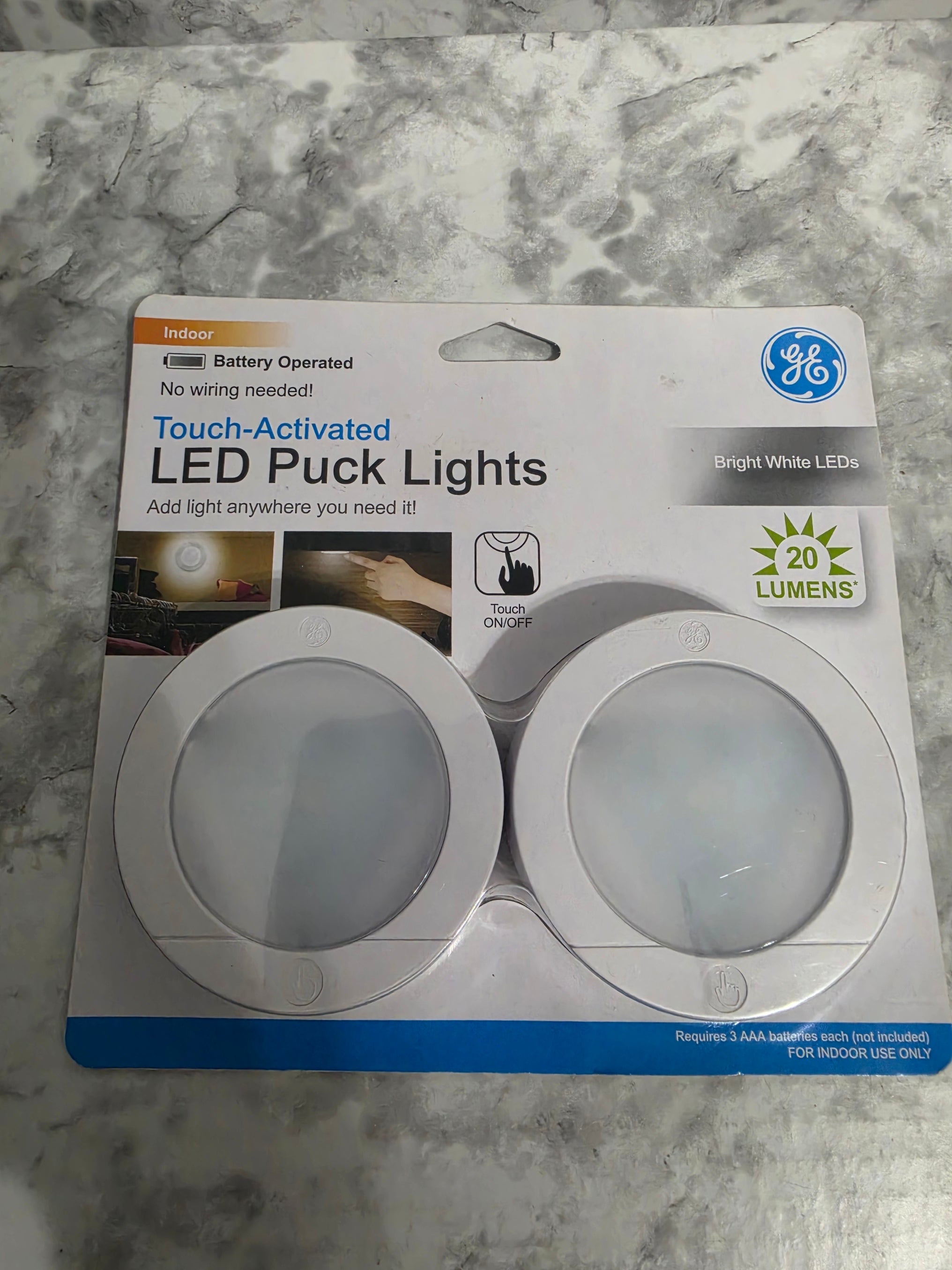 GE LED puck lights packaging on a marble surface