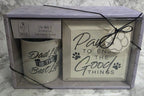 Two candles in a decorative box with text on a marble surface