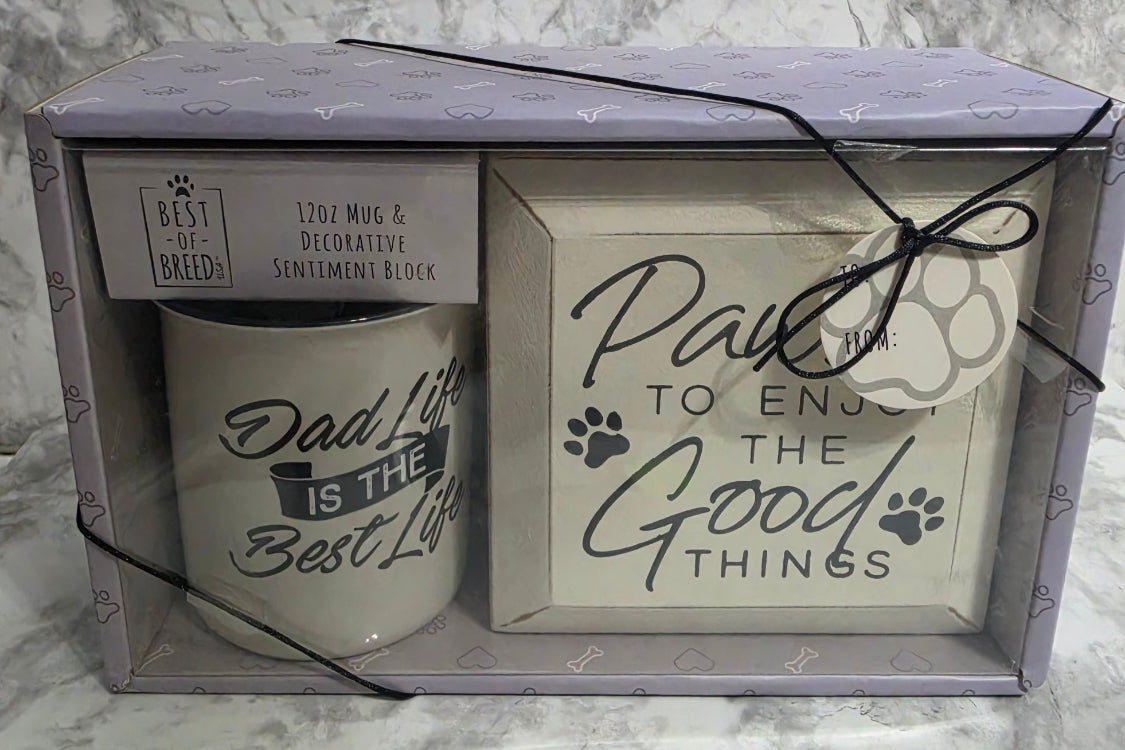 Two candles in a decorative box with text on a marble surface
