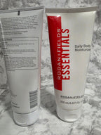 Two tubes of Rodan + Fields Essentials Daily Body Moisturizer on a marble surface.