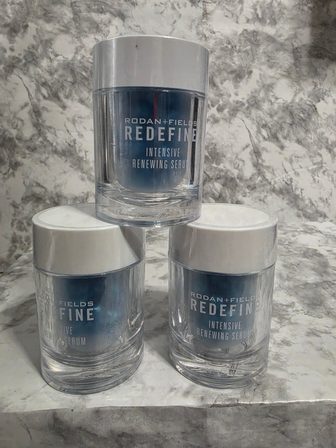 Three bottles of Ralph Lauren Redefine Intensive Renewing Serum on a marble surface.