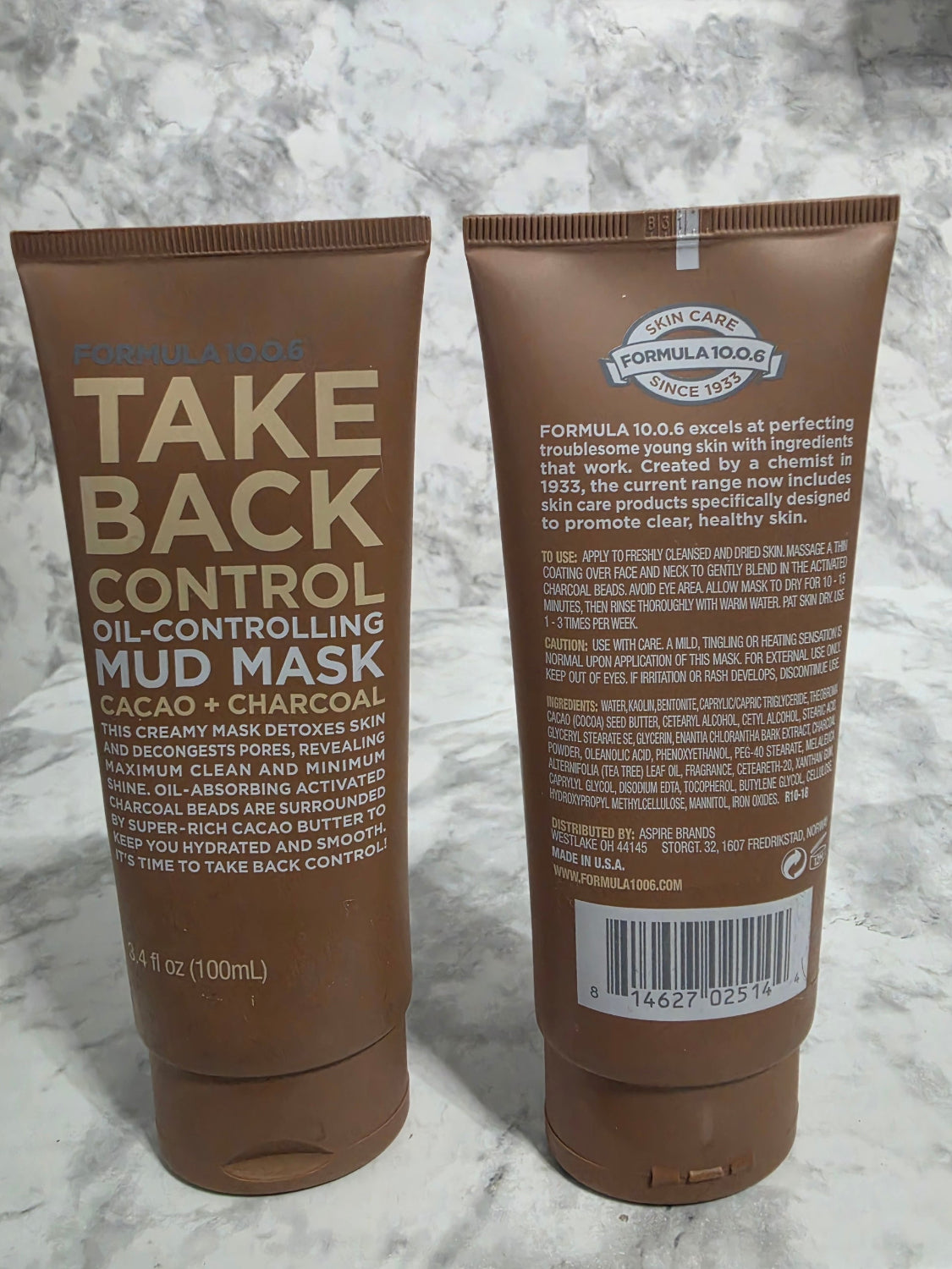 Two brown tubes of 'Take Back Control' mud mask on a marble surface