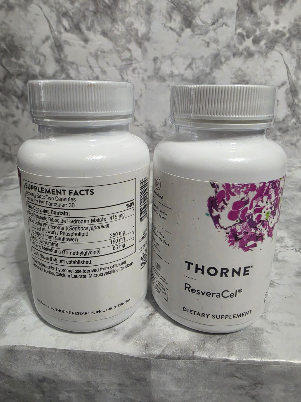 Two Thorne Resvera-Cel dietary supplement bottles on a marble surface