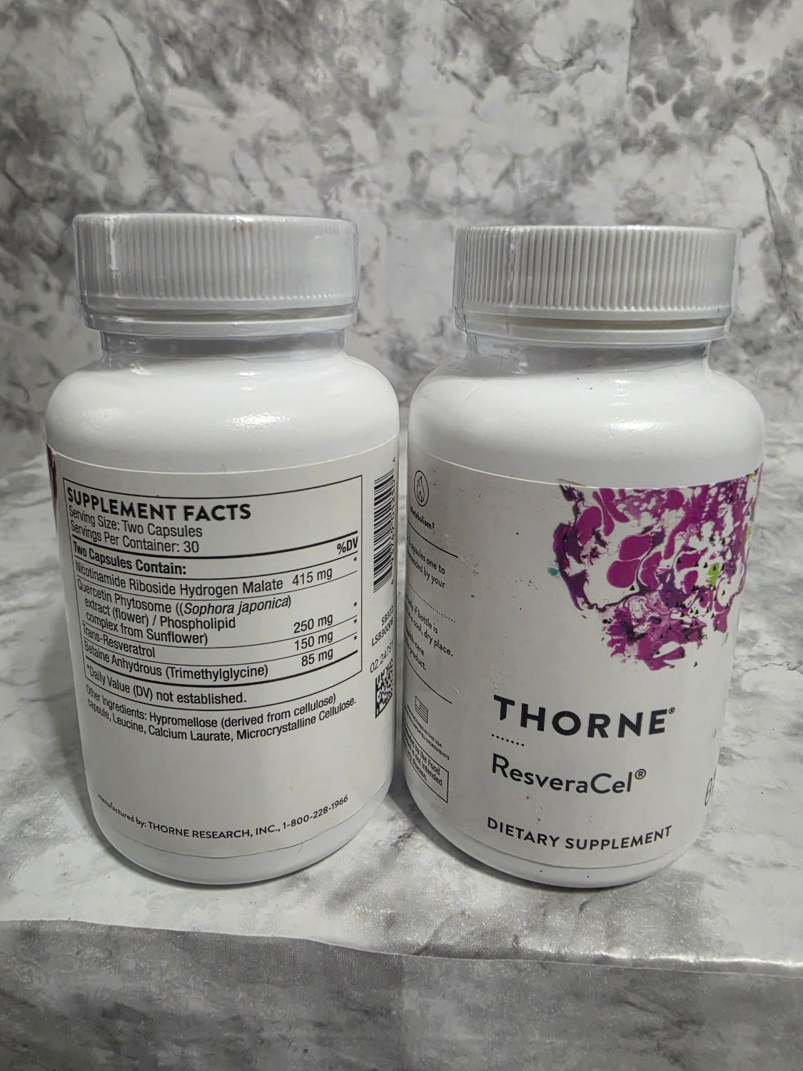 Two Thorne Resvera-Cel dietary supplement bottles on a marble surface