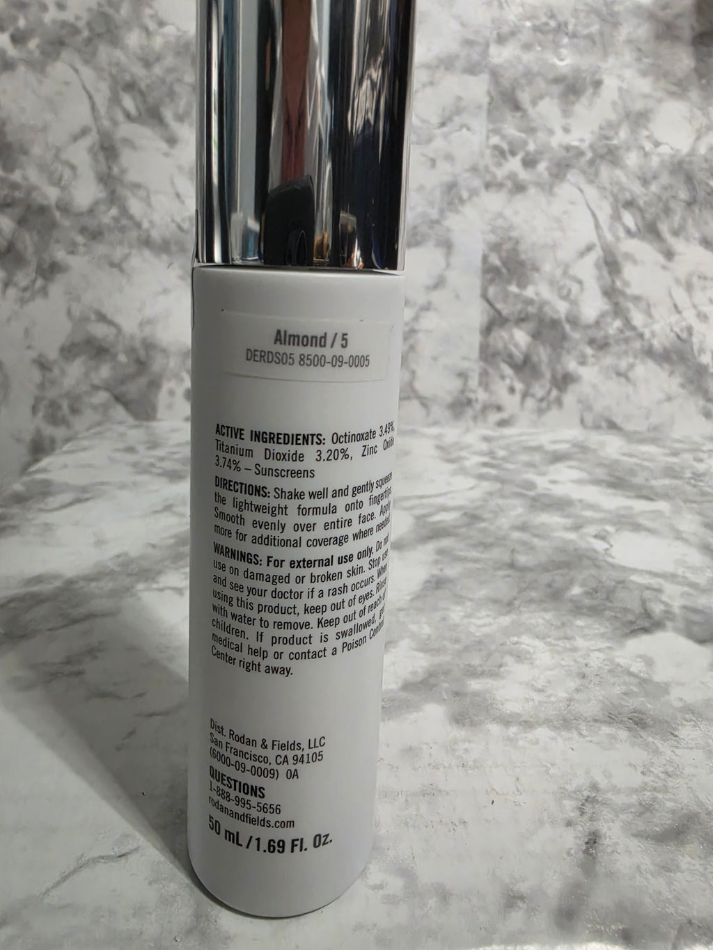 Cosmetic tube with silver cap on a marble surface