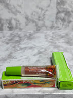 Actual Mary Kay Dual Lip Glaze in Warm Coral with green cap and original colorful retail boxes on gray marble