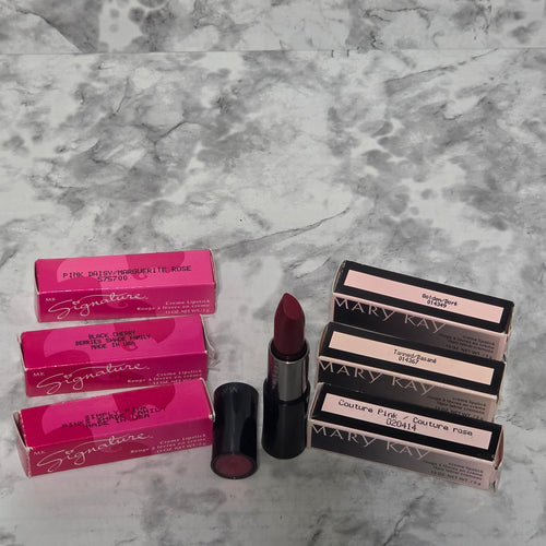 Mary Kay Creme Lipstick discontinued shades collection on marble — pink box Signature and black box classic shades with open Rouge Red lipstick