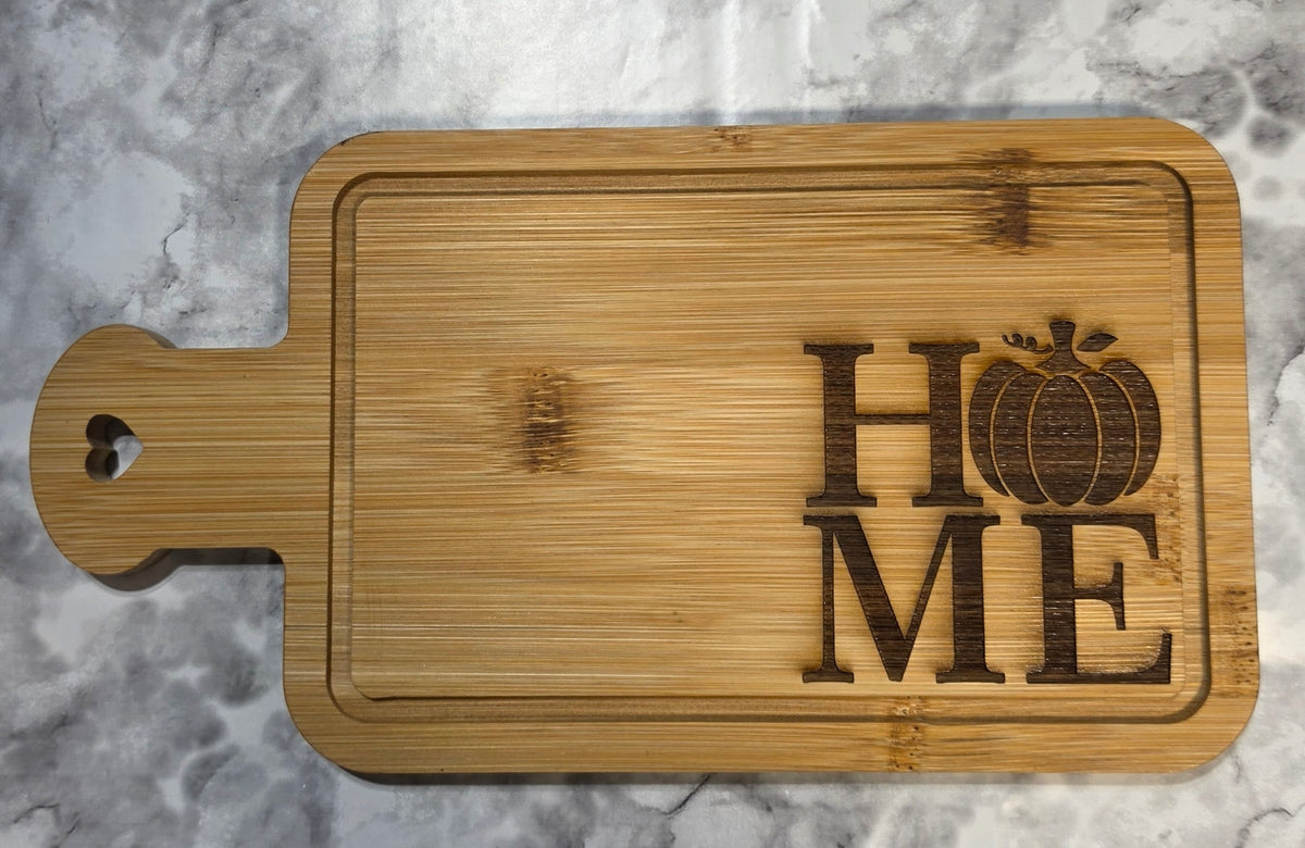 Actual engraved bamboo heart-handle board with HOME lettering and a pumpkin design.
