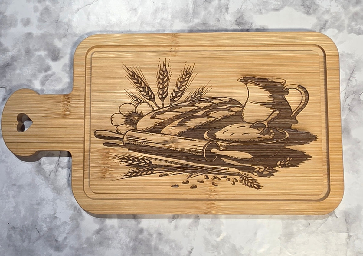 Actual engraved bamboo heart-handle board with bread, wheat and pitcher artwork.