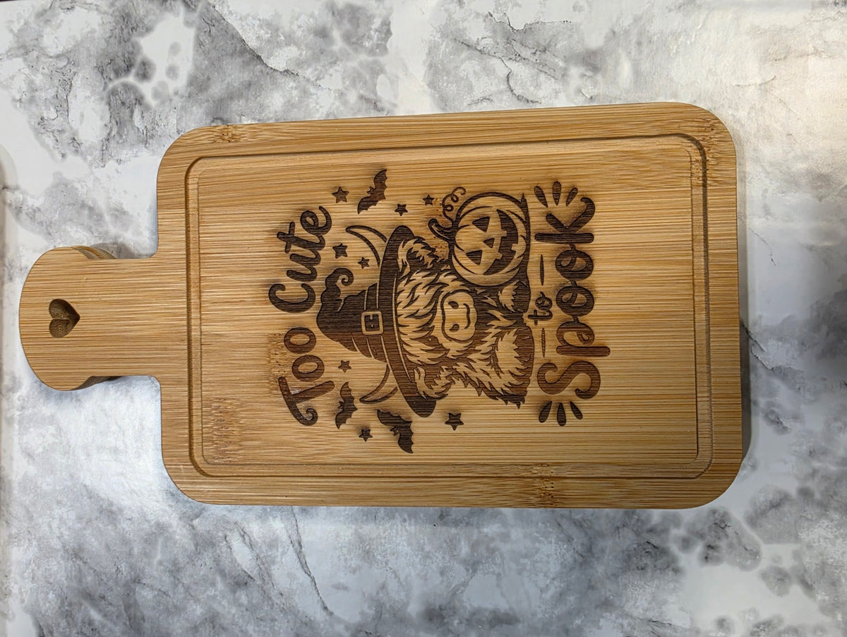 Actual engraved bamboo heart-handle board with a Halloween gnome and Too Cute to Spook lettering.