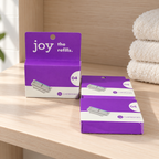 Three Joy four-cartridge refill boxes on a wooden bathroom shelf
