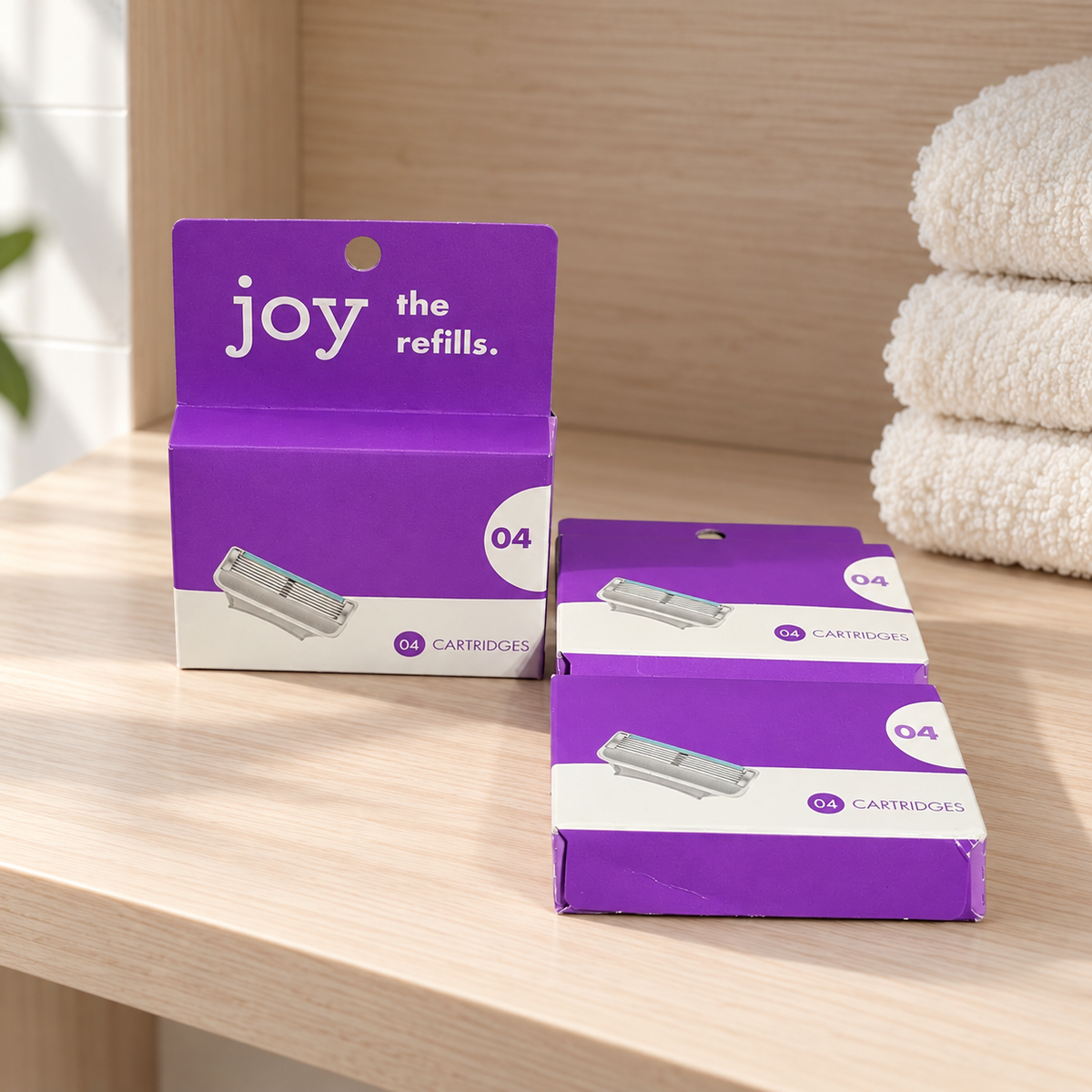 Three Joy four-cartridge refill boxes on a wooden bathroom shelf