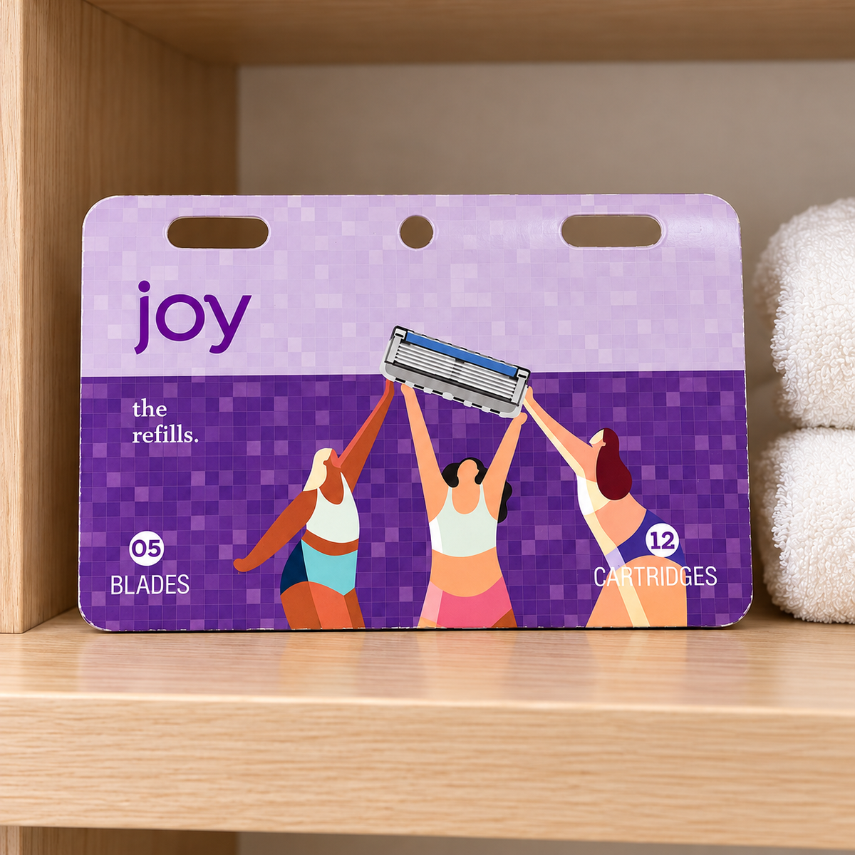 Joy twelve-cartridge refill pack on a bathroom shelf beside white towels